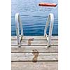Wet footprints on dock with ladder and diving platform at calm summer lake in Ontario Canada