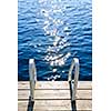 Dock and ladder on calm summer lake with sparkling water in Ontario Canada