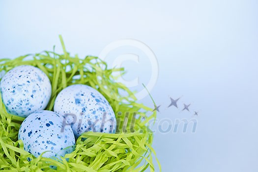 Three blue speckled easter eggs in green paper grass nest with copy space Three blue speckled easter eggs in green paper grass nest with copy space
