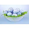 Many blue speckled easter eggs in bowl on green paper grass