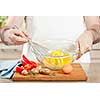 Closeup on man's hands whisking eggs in bowl for cooking omelet with vegetables
