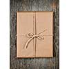 Gift package in brown paper wrapper tied with string on rustic wood background