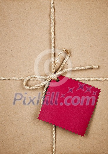 Gift package and red card in brown paper wrapper tied with string close up