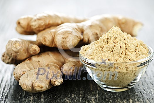 Fresh and ground ginger root spice on wooden table Fresh and ground ginger root spice on wooden table