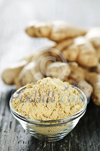 Fresh and ground ginger root spice on wooden table