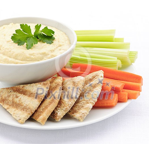 Healthy snack of hummus dip with pita bread slices and vegetables