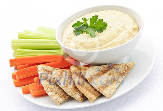 Healthy snack of hummus dip with pita bread slices and vegetables