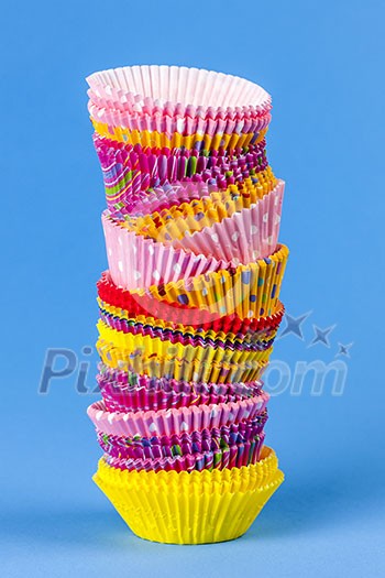 Tall stack of colorful muffin or cupcake cups on blue background Tall stack of colorful muffin or cupcake cups on blue background