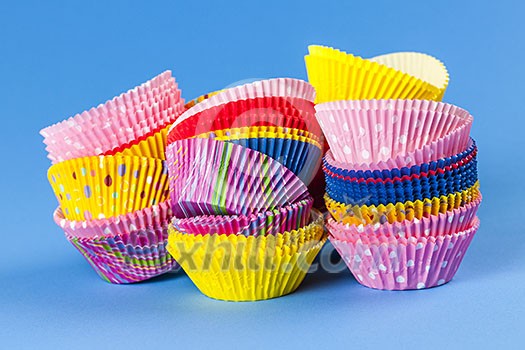 Several stacks of colorful muffin or cupcake cups on blue background