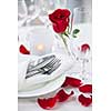 Romantic table setting with rose petals plates and cutlery