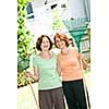 Mother and daughter holding rakes gardening outside