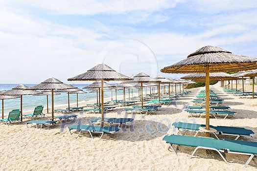 Rows of umbrellas on empty seaside beach in Greece