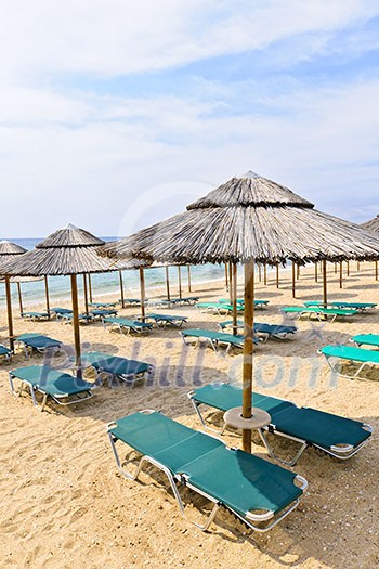Straw umbrellas on empty seaside beach in Greece