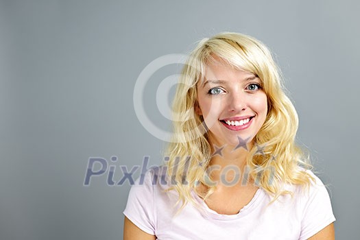 Portrait of smiling young blonde caucasian woman on grey background