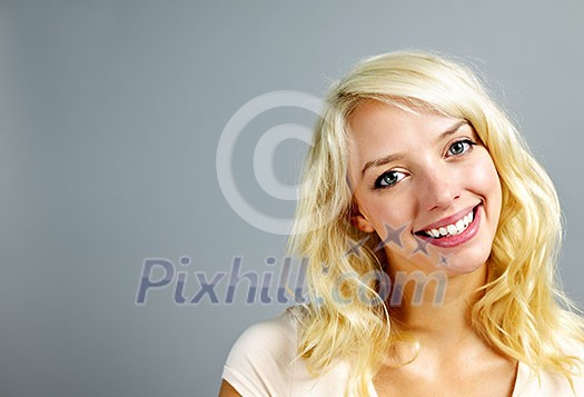 Portrait of smiling young blonde caucasian woman on grey background