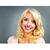 Portrait of smiling young blonde caucasian woman on grey background