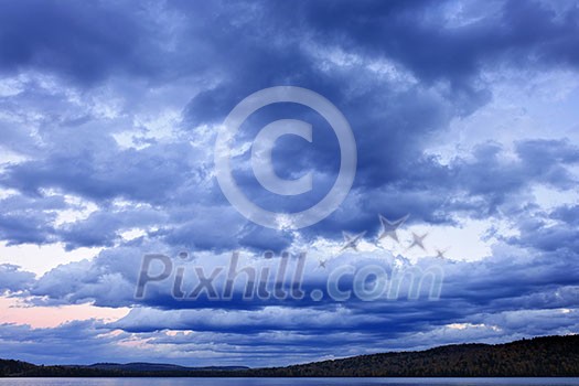 Blue cloudy dramatic sky at sunset over forest wilderness in Algonquin Park, Canada