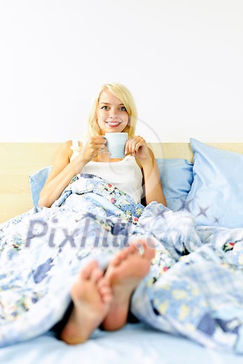 Happy blonde woman drinking coffee and relaxing in bed in the morning Happy blonde woman drinking coffee and relaxing in bed in the morning