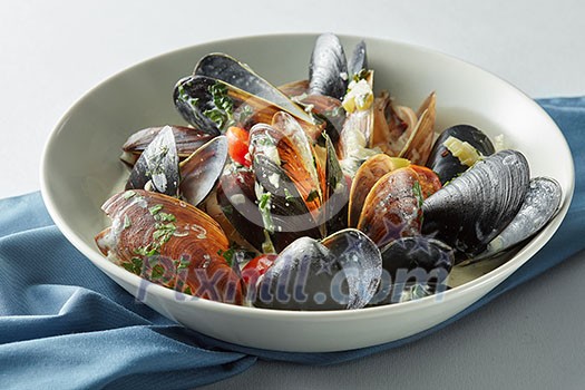 dish of mussels pics with tomato sauce, open, ready to eat on a light background dish of mussels pics with tomato sauce, open, ready to eat on a light background