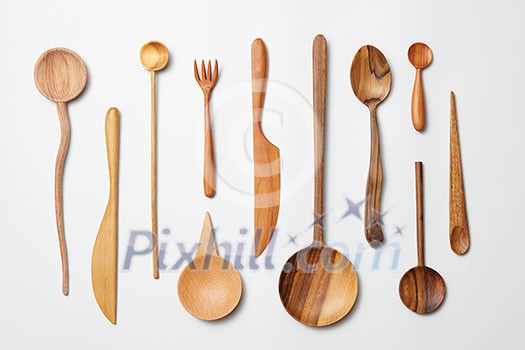 Wooden spoons, knives, forks on a white background