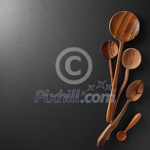Wood spoons on black board background. Space for text