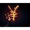 Burning yen sign in businessman palm on dark background