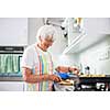 Senior woman/grandmother cooking in a modern kitchen (shallow DOF; color toned image)