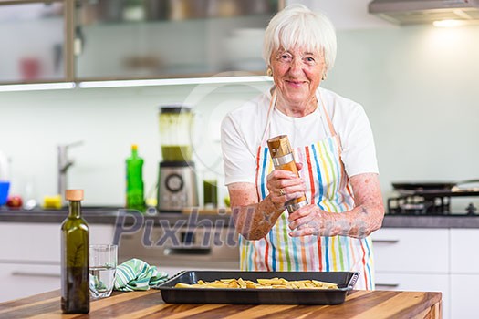 Senior woman/grandmother cooking in a modern kitchen (shallow DOF; color toned image)