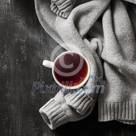 grey cozy knitted sweater with to cup of tea on a wooden black table grey cozy knitted sweater with to cup of tea on a wooden black table