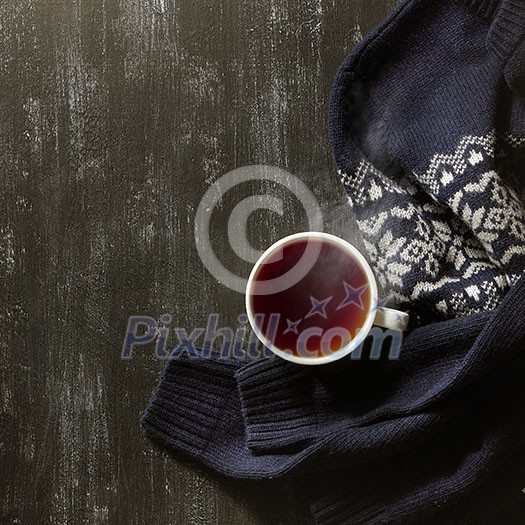Cozy winter home background, cup of hot tea and warm knitted sweater on black background. Cozy winter home background, cup of hot tea and warm knitted sweater on black background.