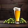 Still life with a keg of beer and green hop on a dark brown wooden background