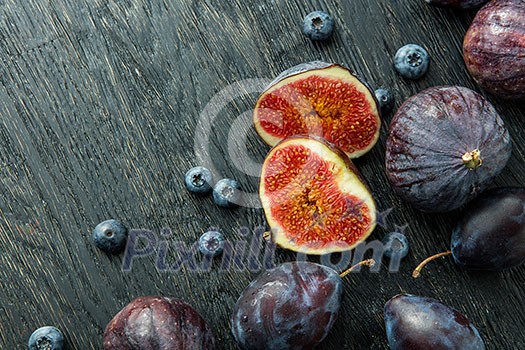 Fresh figs and blueberries, black wood background