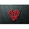 Red dogwood berries as a full heart shape isolated on black wooden background. Valentines day concept