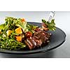salad with pumpkin, grilled meat duck and fresh green salad on a plate and fork with salad