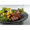salad with pumpkin, grilled meat duck and fresh green salad on a plate and fork with salad