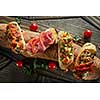 Italian crostini with various toppings serving on baguette on wooden black background, top view