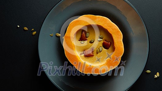 Fresh cooked pumpkin soup on Halloween on a black table Fresh cooked pumpkin soup on Halloween on a black table