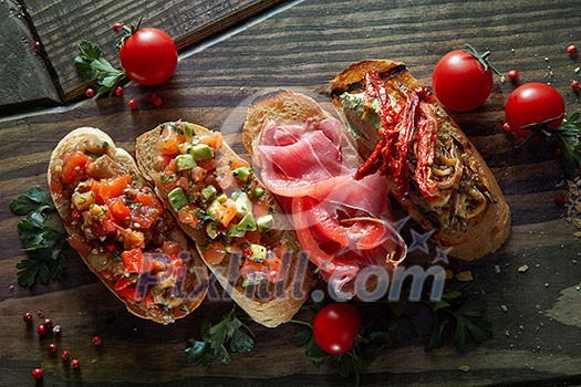 Italian crostini with various toppings on wooden black background, top view Italian crostini with various toppings on wooden black background, top view