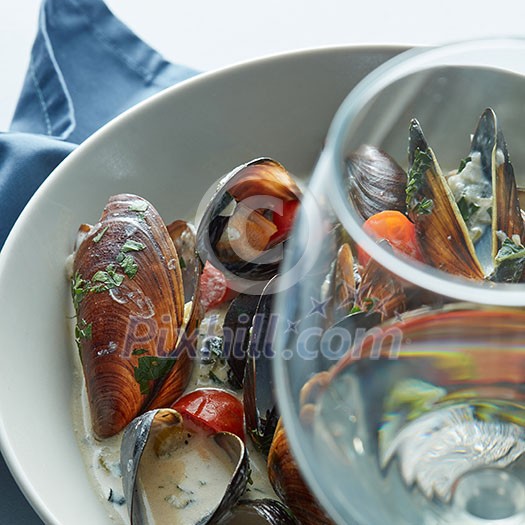Delicious mussels with sauce and a glass of white wine Delicious mussels with sauce and a glass of white wine