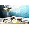 Oysters in a white plate with lemon and a glass of wine