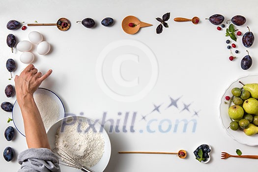 Baking background with ingredients for fruit cake and woman take egg in the frame in white background