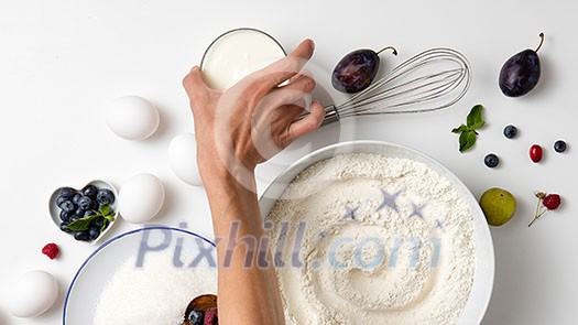Raw ingredients for baking pie with berries. Woman hand take bowl with sugar on a white background