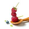 Raspberry in wooden spoon and blueberri on isolated white background