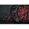 black plate with healthy berries on a black wooden background