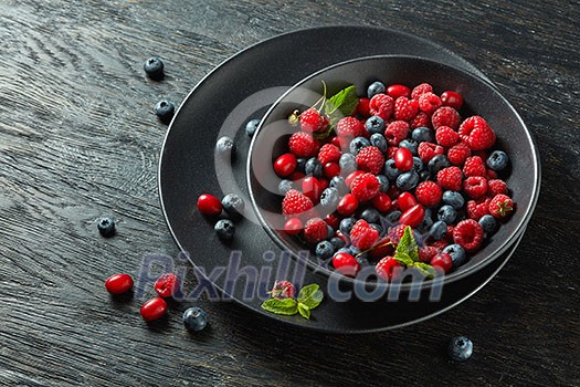 fresh berries in a black ceramic bowl on black background