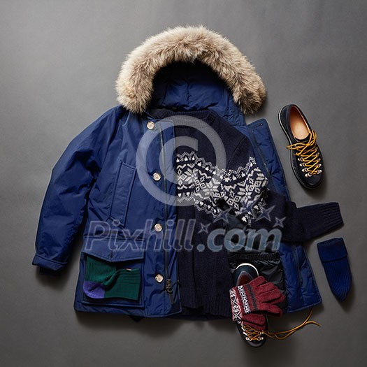 Set of beautiful winter male clothes on a black background. Winter sweater, shoes, gloves, jacket and cap