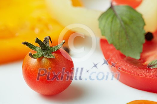 Tomato with green tail and pepper slices on a white background