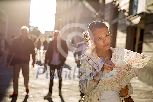 Gorgeous female tourist with a map discovering a foreign city (shallow DOF; color toned image)