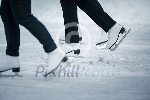 Young woman ice skating outdoors on a pond on a freezing winter day - detail of the legs (color toned image) Young woman ice skating outdoors on a pond on a freezing winter day - detail of the legs (color toned image)