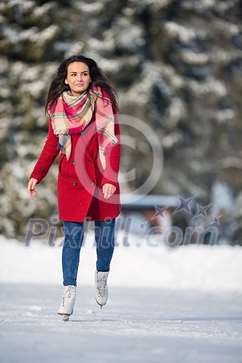 Young woman ice skating outdoors on a pond on a freezing winter day (color toned image; motion blurred image) Young woman ice skating outdoors on a pond on a freezing winter day (color toned image; motion blurred image)